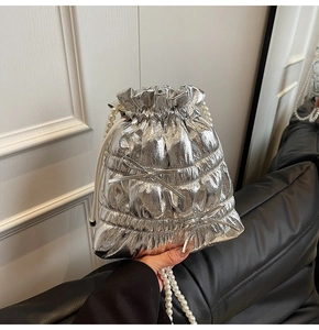Close-up of silver pleated drawstring bucket bag with pearl chain and bow details