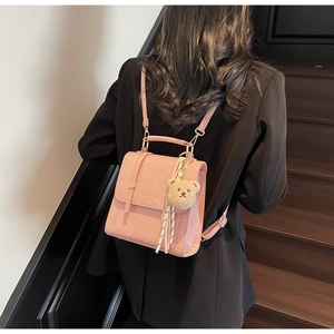 Detail view of pink square backpack with plush bear charm worn by model in black blazer