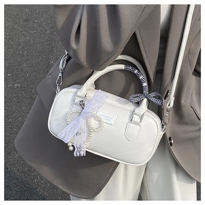 Détail d'un sac bowling blanc avec nœud en dentelle, breloque perle et poignée en foulard