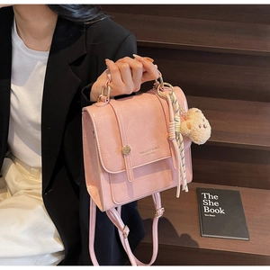 Pink glossy faux leather handbag detail with bear charm and checkered braided handle
