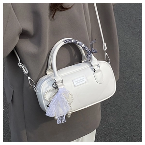 Sac bowling blanc avec poignée ruban et breloque perle porté par un mannequin