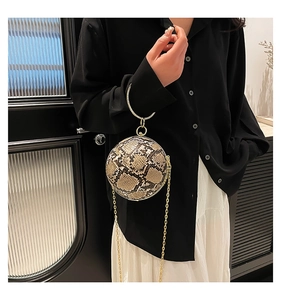 Detail of snake skin pattern spherical handbag with gold ring handle and metal chain