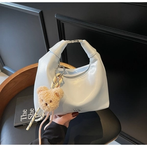 Detail of light blue crescent bag with silver buckle and cute plush bear charm accessory