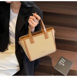 Detail of woven beige texture and brown leather trim on a stylish bucket bag