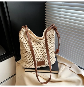 Close-up of woven straw tote bag with brown leather strap and brand logo patch