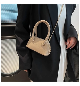Detail of beige shell bag with lychee texture and gold bead chain strap