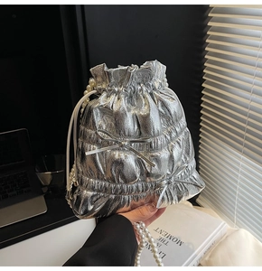Detail of silver metallic drawstring bag with pearl handle and bow embellishments