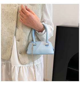 Detail of light blue shell crossbody bag with litchi grain leather and gold chain