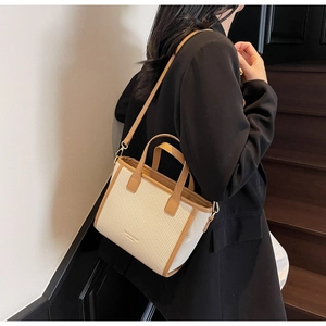 Detail of the woven canvas bucket bag with camel leather trim shown on a model