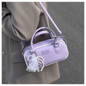 Détail du mini sac bowling violet clair avec pendentif perle et ruban à carreaux