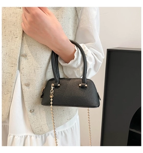 Detail view of black lychee grain leather shell bag with elegant gold bead metal chain