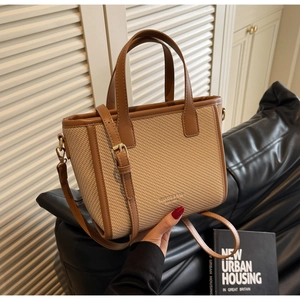 Close-up of straw and leather bucket bag featuring a gold buckle and adjustable strap
