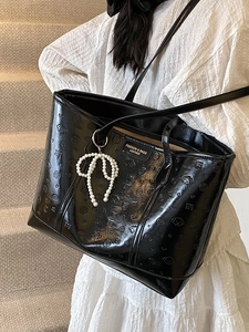 Large black glossy tote bag with embossed cartoon patterns and pearl bow charm accessory