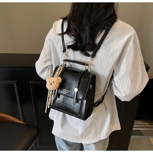 Detail of minimalist black mini backpack showing glossy texture and cute teddy charm