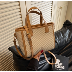 Detailed macro view of woven canvas texture and brown leather trim on a chic tote bag