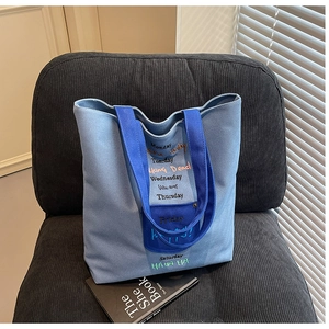 Detail of light blue canvas tote bag with contrast handles and colorful embroidery
