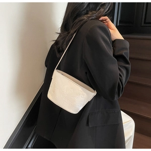 Vue détaillée des motifs de papillons et fleurs embossés sur le sac seau blanc chic