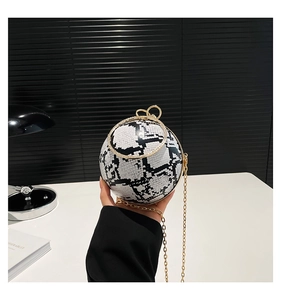 Detail view of snakeskin pattern spherical bag with gold ring handle and bow clasp