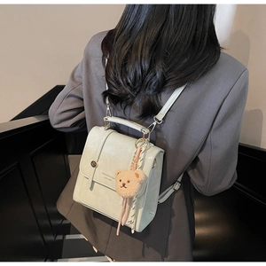 Mint green leather backpack with bear charm and adjustable straps shown on a model