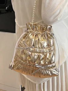 Metallic gold drawstring bucket bag with pearl strap and silver bow accents