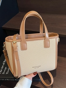 Elegant beige and brown leather bucket bag with top handle and shoulder strap on wood stairs