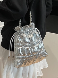 Metallic silver drawstring bucket bag with quilted texture and decorative pearl handle