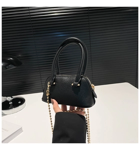 Close-up of black leather shell bag with gold chain strap in minimalist modern setting