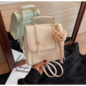 Detailed mirror shot of cream and mint mini backpacks with plush bear charms and silk ribbons