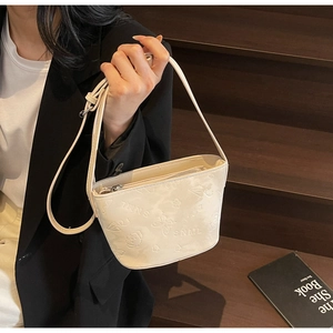 Détail du sac seau crème avec motifs de papillons embossés et fermeture éclair argentée