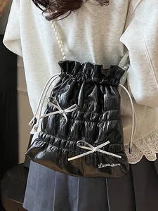 Chic black glossy drawstring bucket bag with pearl strap and silver bow detail