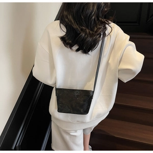 Détail d'un sac seau noir minimaliste avec texture gaufrée discrète sur un modèle