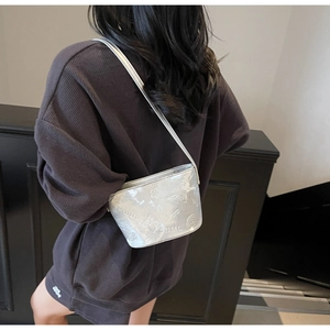 Détails d'un sac seau argenté avec motifs floraux gaufrés et finition métallique
