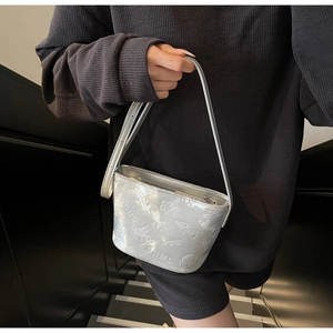 Détail du sac seau argenté avec motifs gaufrés et finition métallique brillante