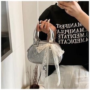 Detail of silver metallic Boston bag featuring embossed patterns and large lace bow decoration