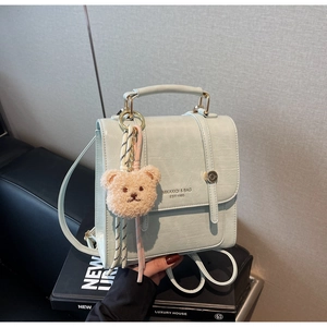 Detail of mint green leather backpack with top handle and cute plush bear keychain