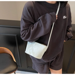 Détail d'un sac seau vert menthe avec motif embossé et inscription SNML sur PU