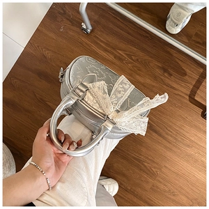 Detailed view of silver Boston bag with 3D embossed stars and large white lace bow detail