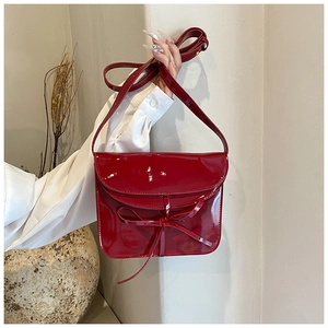 Detail view of the red oil-wax leather bag featuring a chic bow and glossy finish