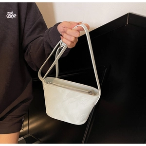 Détail d'un sac seau blanc en cuir embossé avec motifs 3D mignons et fermeture éclair argentée