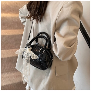 Detail of black embossed Boston bag with white lace bow charm and premium metal hooks