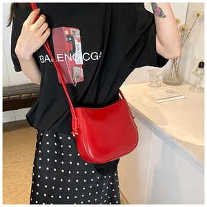 Dettaglio borsa hobo rossa in pelle cerata con finitura lucida su maglia nera