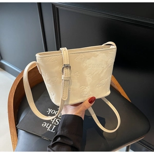 Gros plan des motifs papillon et chiot gaufrés sur un sac seau de couleur beige