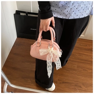 Detailed close-up of pink Boston bag with embossed patterns and white lace bow
