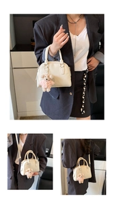 Detail of cream bowling bag showing top handles, shoulder strap and cute bear charm