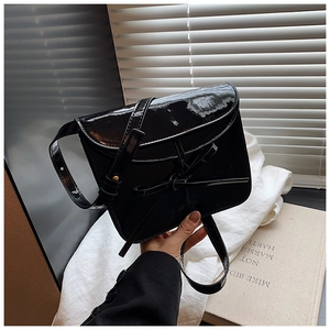 Detail of black glossy faux leather ballet bag with ribbon bow and adjustable strap