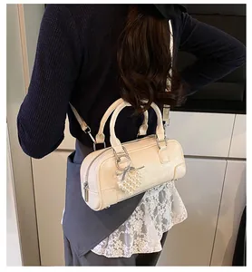 Detail of cream Boston bag featuring cracked texture PU leather and pearl heart charm