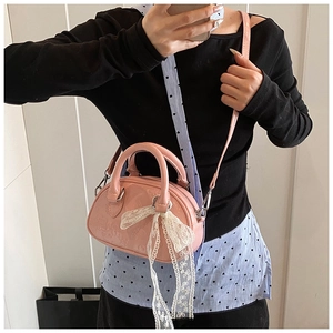 Detail of pink embossed PU leather bag featuring a delicate white lace bow accessory