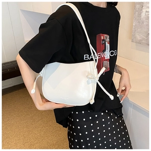 Dettaglio della borsa a secchiello in pelle bianca con nodi laterali e design minimalista