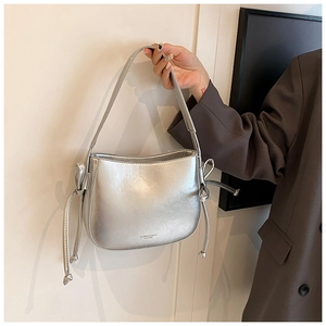 Dettaglio borsa a secchiello in pelle argentata effetto cerato con fiocchi a coulisse laterali