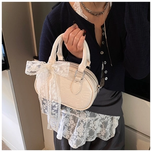 Detail of cream Boston bag featuring embossed leather textures and a large lace bow